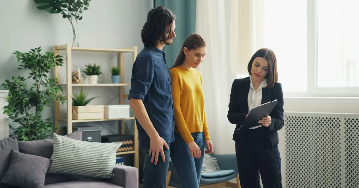 A real estate agent with a tablet showing a home to a couple.