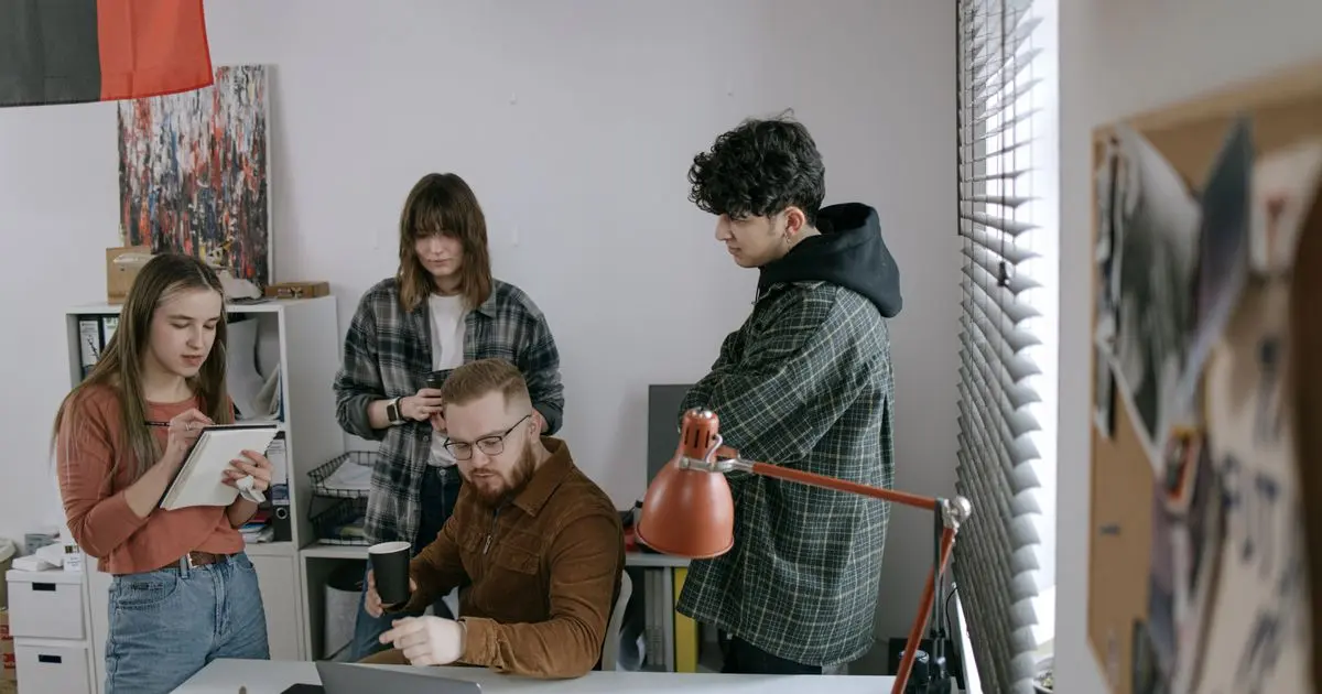 A small team gathered around a desk, working together on a project.