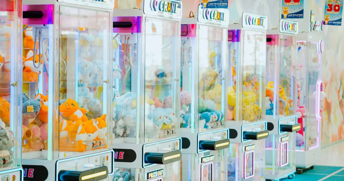 A row of brightly lit arcade claw machines filled with plush toys.