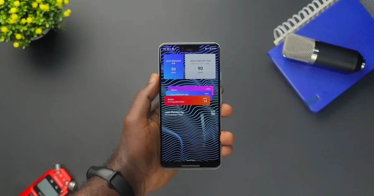 A hand holding a smartphone full of notifications over a desk.