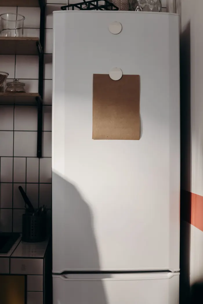 A single plan sheet held to a white fridge door with magnets in a home kitchen.
